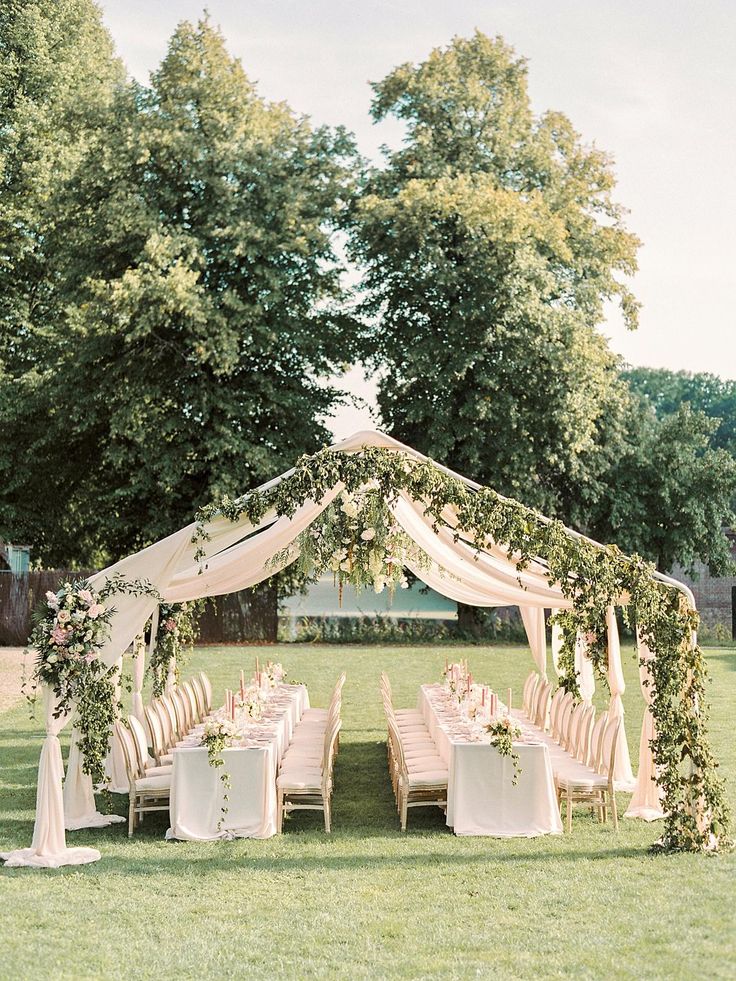 an outdoor wedding setup with white linens and greenery