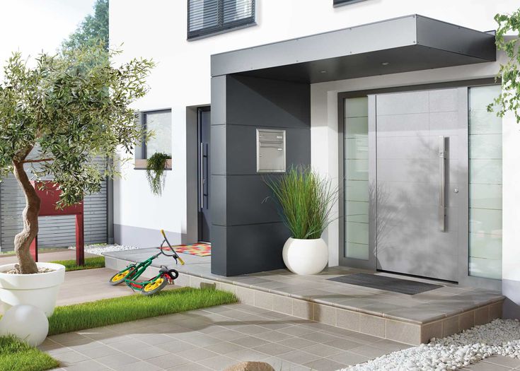 a bicycle is parked in front of a modern house with grass and rocks on the ground