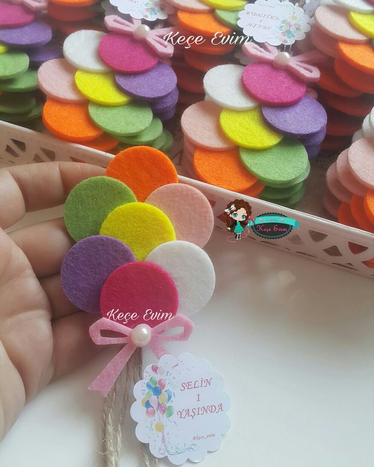 a hand holding a bunch of colorful felt hearts with tags attached to the top of them