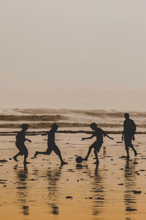 silhouettes of children playing soccer on the beach