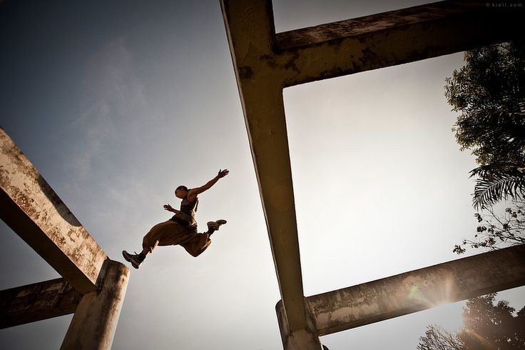 a man jumping in the air on top of a wooden structure with his arms outstretched