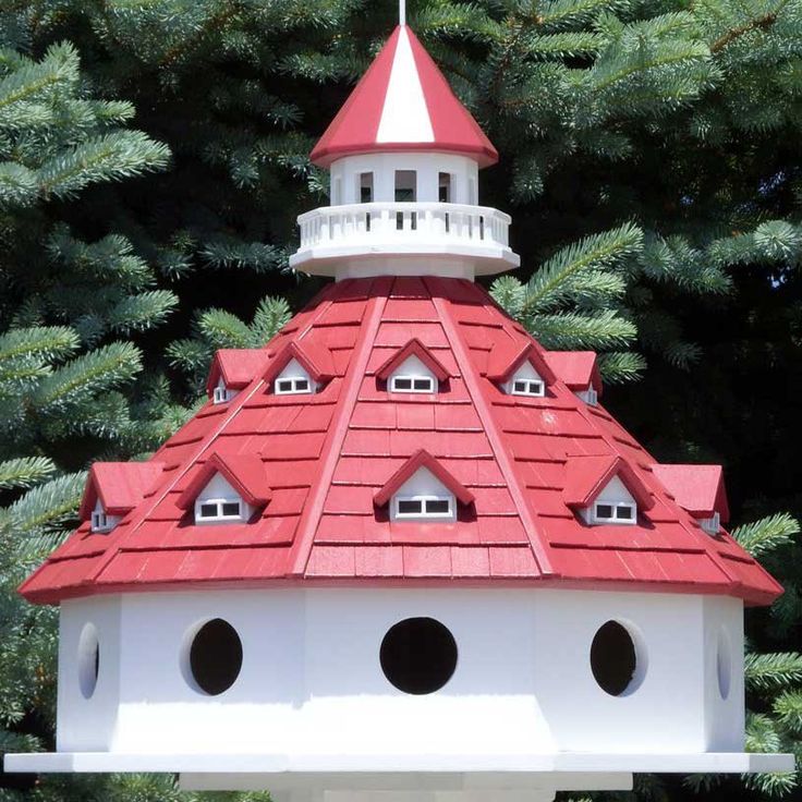 a red and white bird house in front of some trees