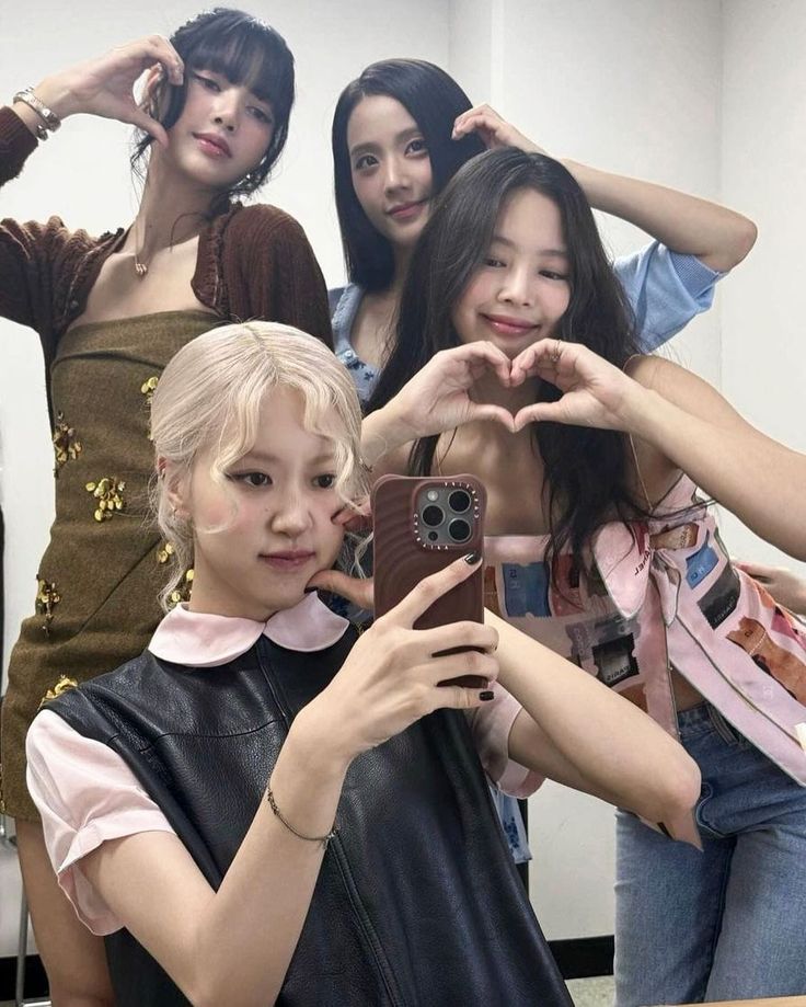 four young women are taking pictures with their cell phones in front of a mirror,