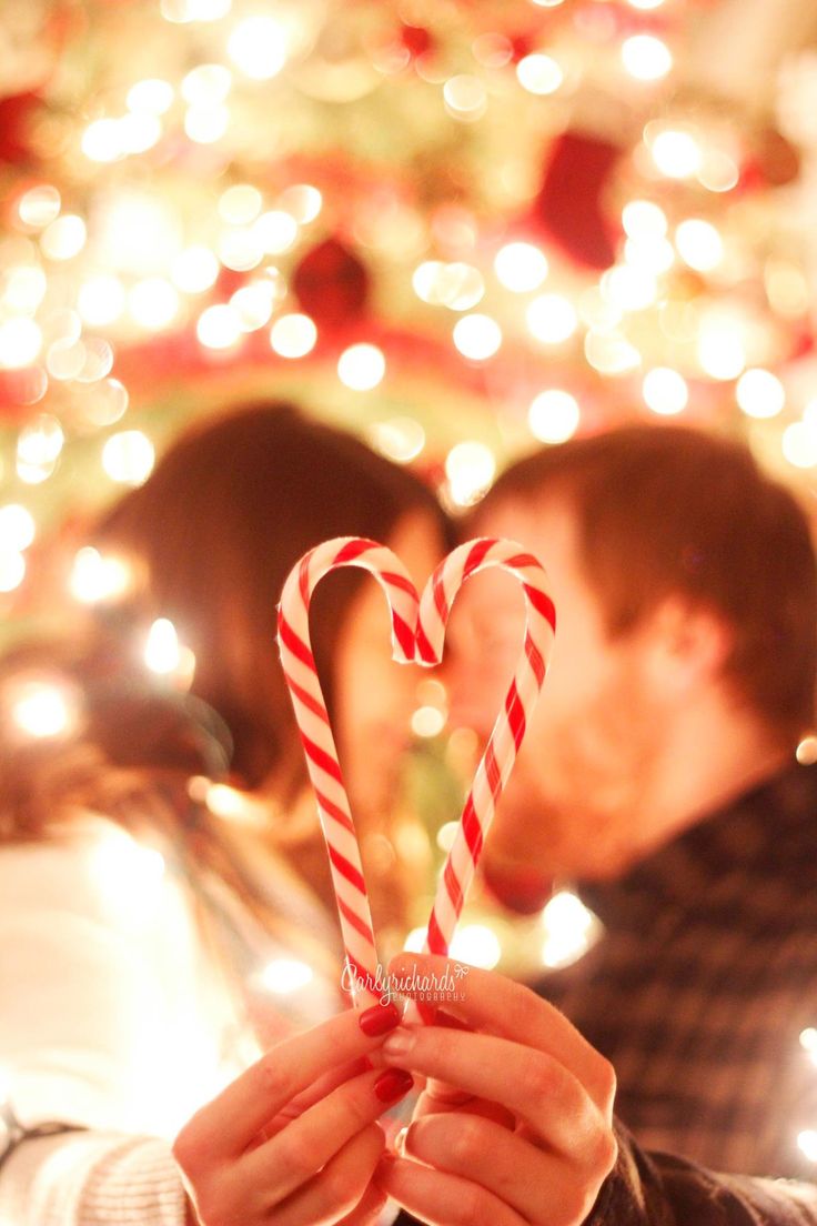 a person holding a candy cane in front of a christmas tree