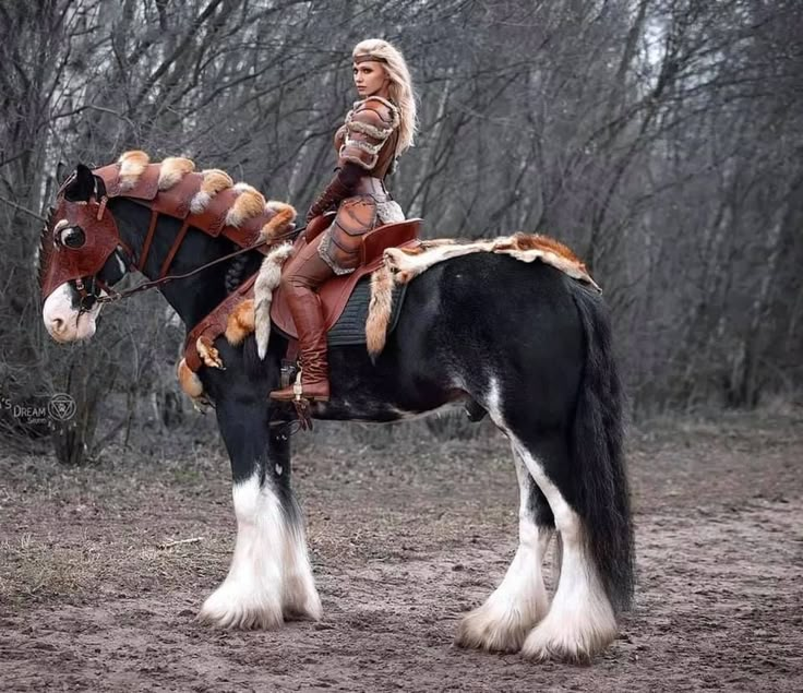 a woman dressed in native american clothing sitting on top of a black and white horse