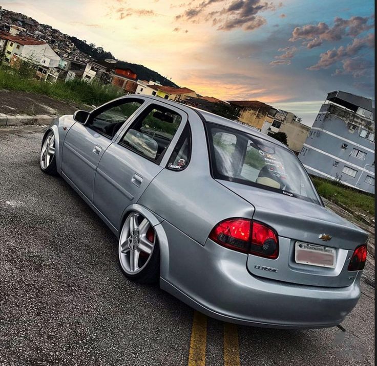 a silver car parked in a parking lot next to some houses and buildings at sunset