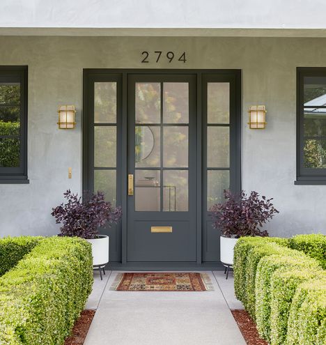 the front door of a house with two large hedges