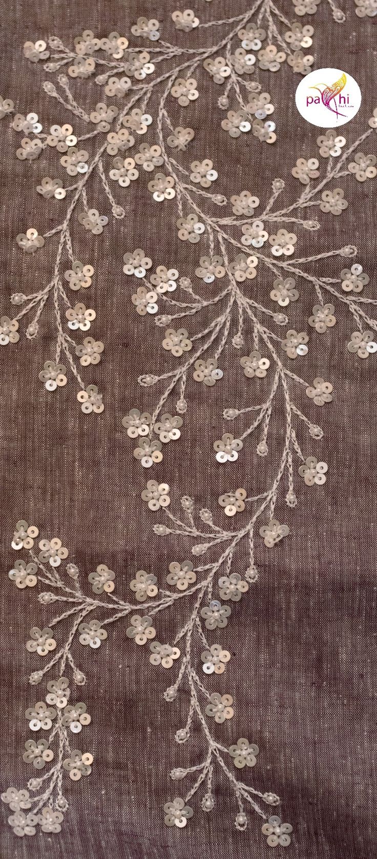 an embroidered fabric with flowers and leaves on brown background, closeup view from the bottom