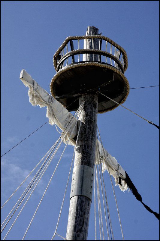 the mast of an old sailing ship against a blue sky