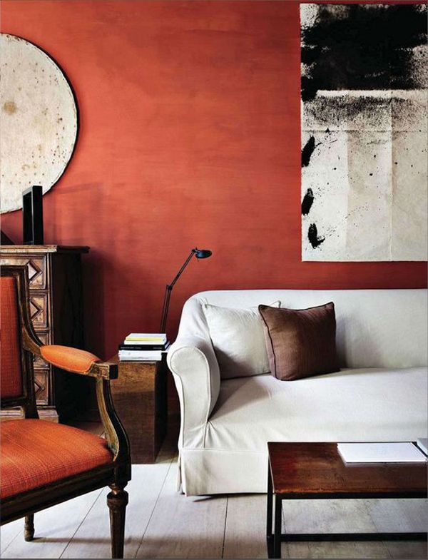 a living room with red walls, white couches and a painting on the wall