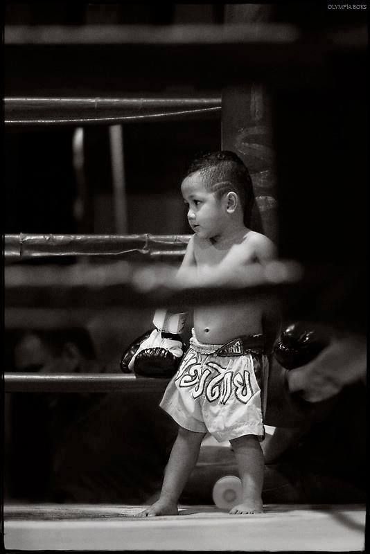 a young boy standing next to a boxing ring