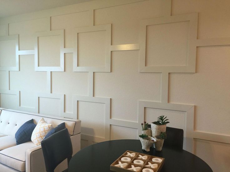 a living room filled with furniture and walls covered in white paneled art work on the wall