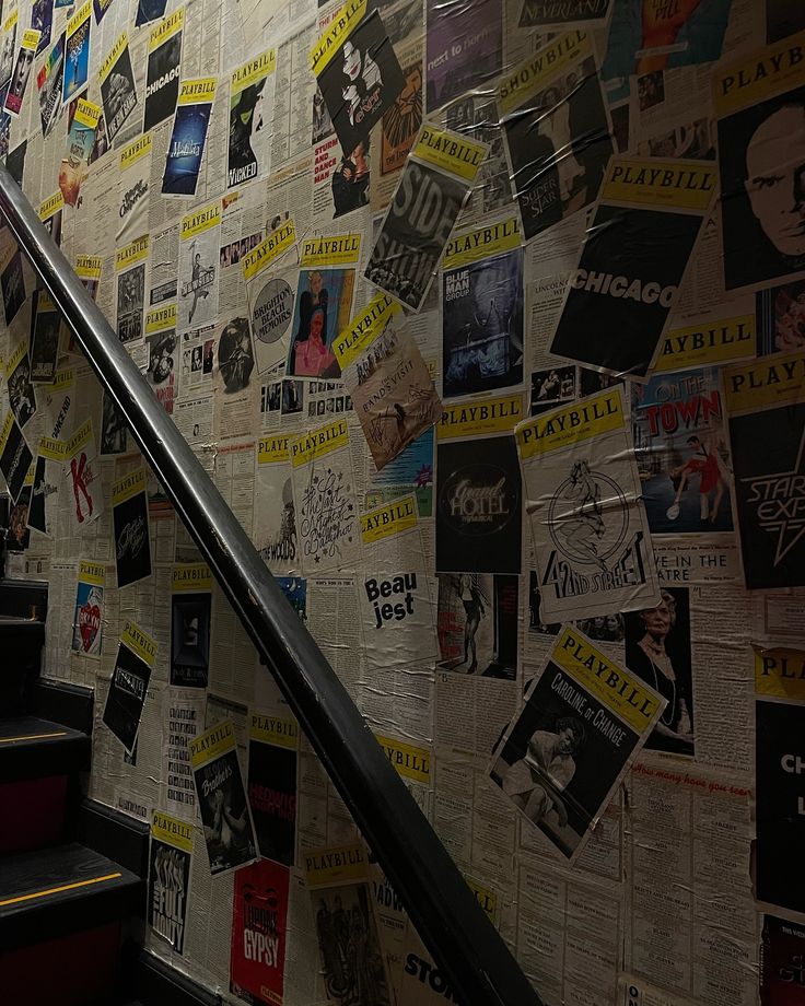 an escalator with many posters on the wall next to it and some stairs