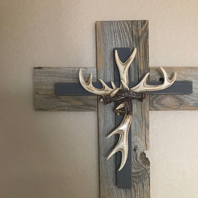 a wooden cross with deer antlers mounted to it's sides on a wall