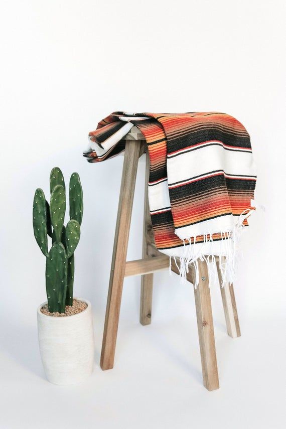 a cactus sitting next to a blanket on a stool