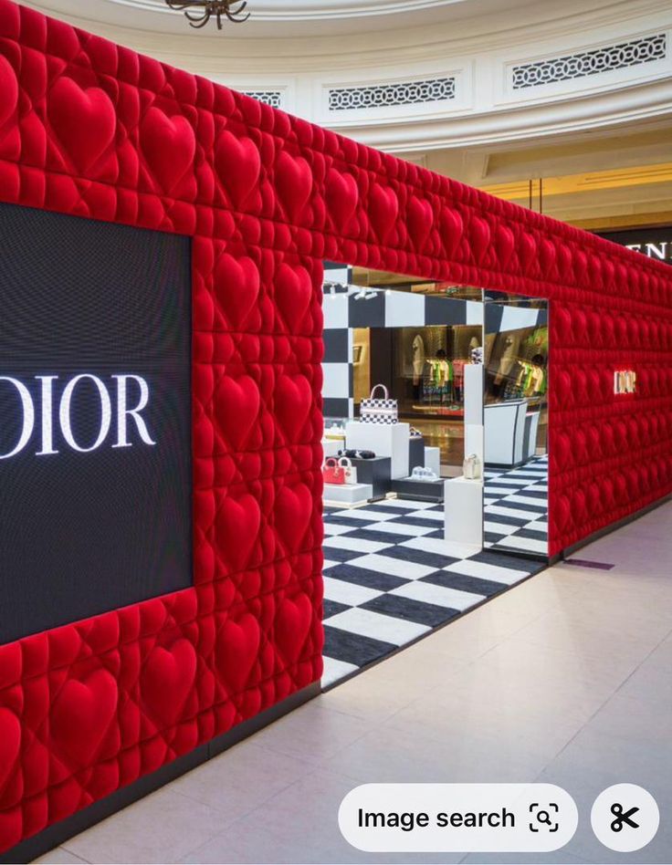 a red and black wall with the word dior on it in front of a store