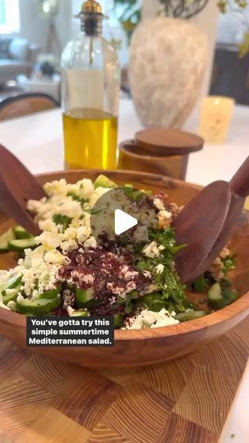 a wooden bowl filled with food on top of a table next to a bottle of olive oil