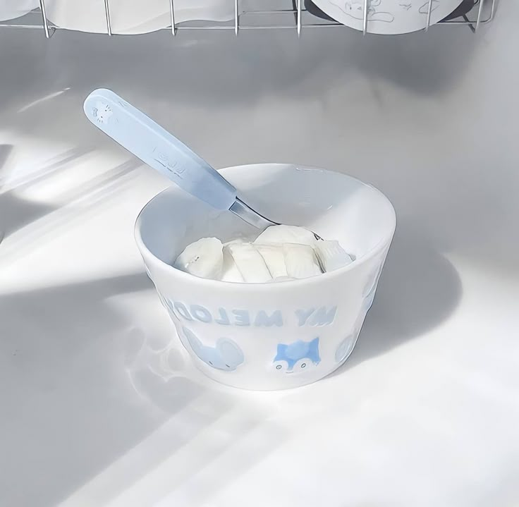 a white bowl filled with marshmallows and a blue handled knife in it