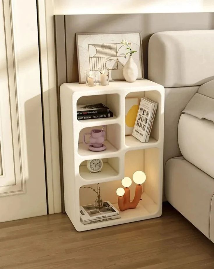 a white shelf with candles and pictures on it next to a bed in a room