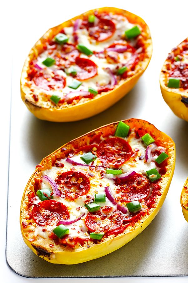 four baked stuffed peppers sitting on top of a white tray with green onions and cheese