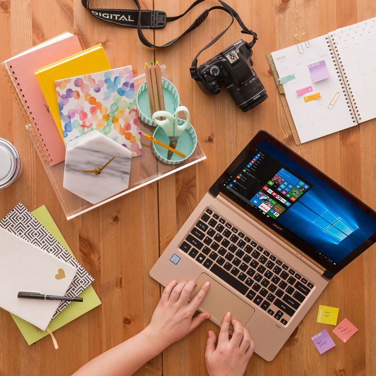 a person sitting at a table with a laptop and various office supplies on top of it