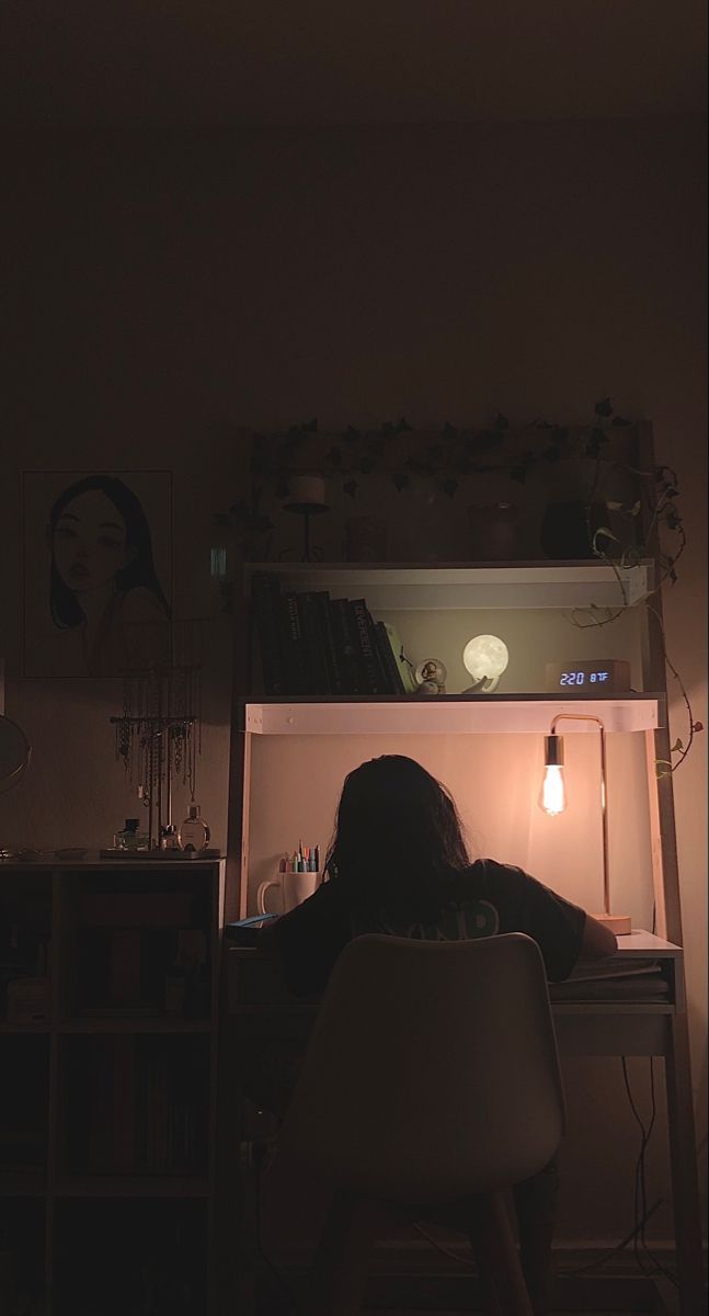 a woman sitting at a desk in front of an open refrigerator