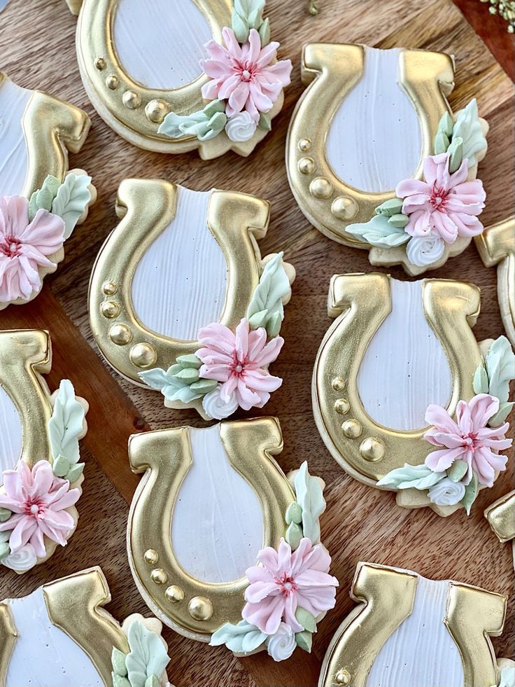 decorated cookies are arranged in the shape of horseshoes with pink flowers and leaves on them