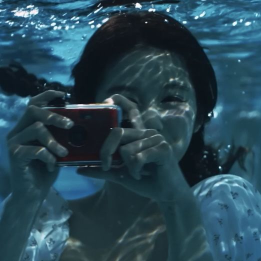 a woman taking a photo with her cell phone under the water's surface,