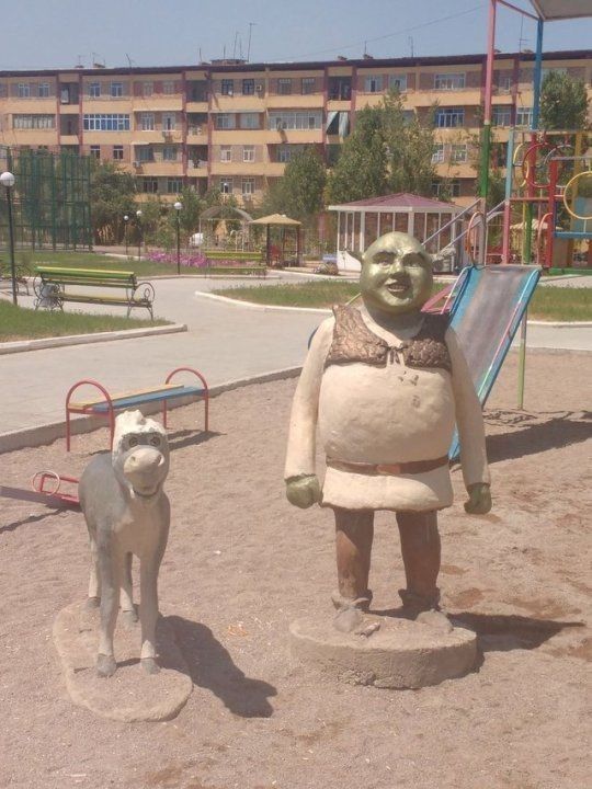 a statue of a baby yoda and a dog in front of a playground area