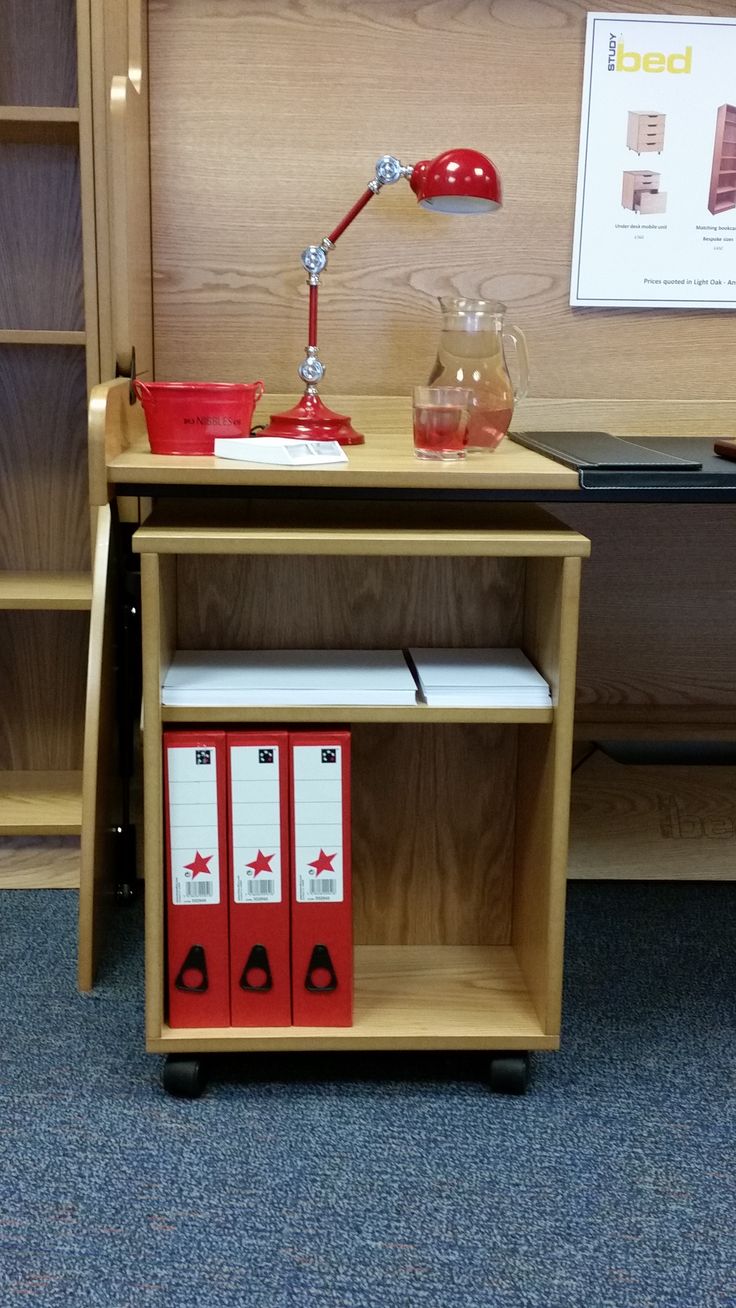 a wooden shelf with three red boxes on it and a lamp in the corner next to it