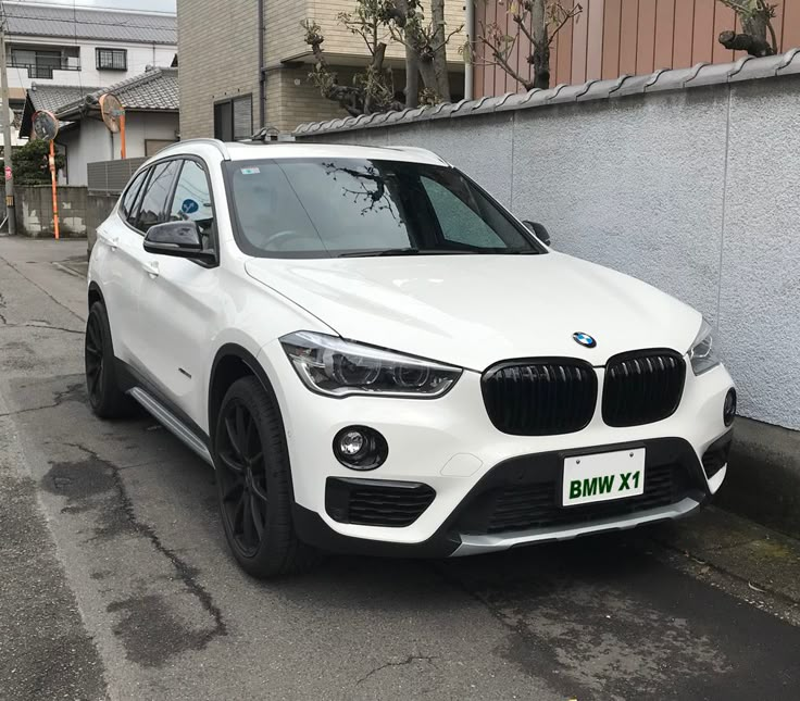 a white bmw suv is parked on the street