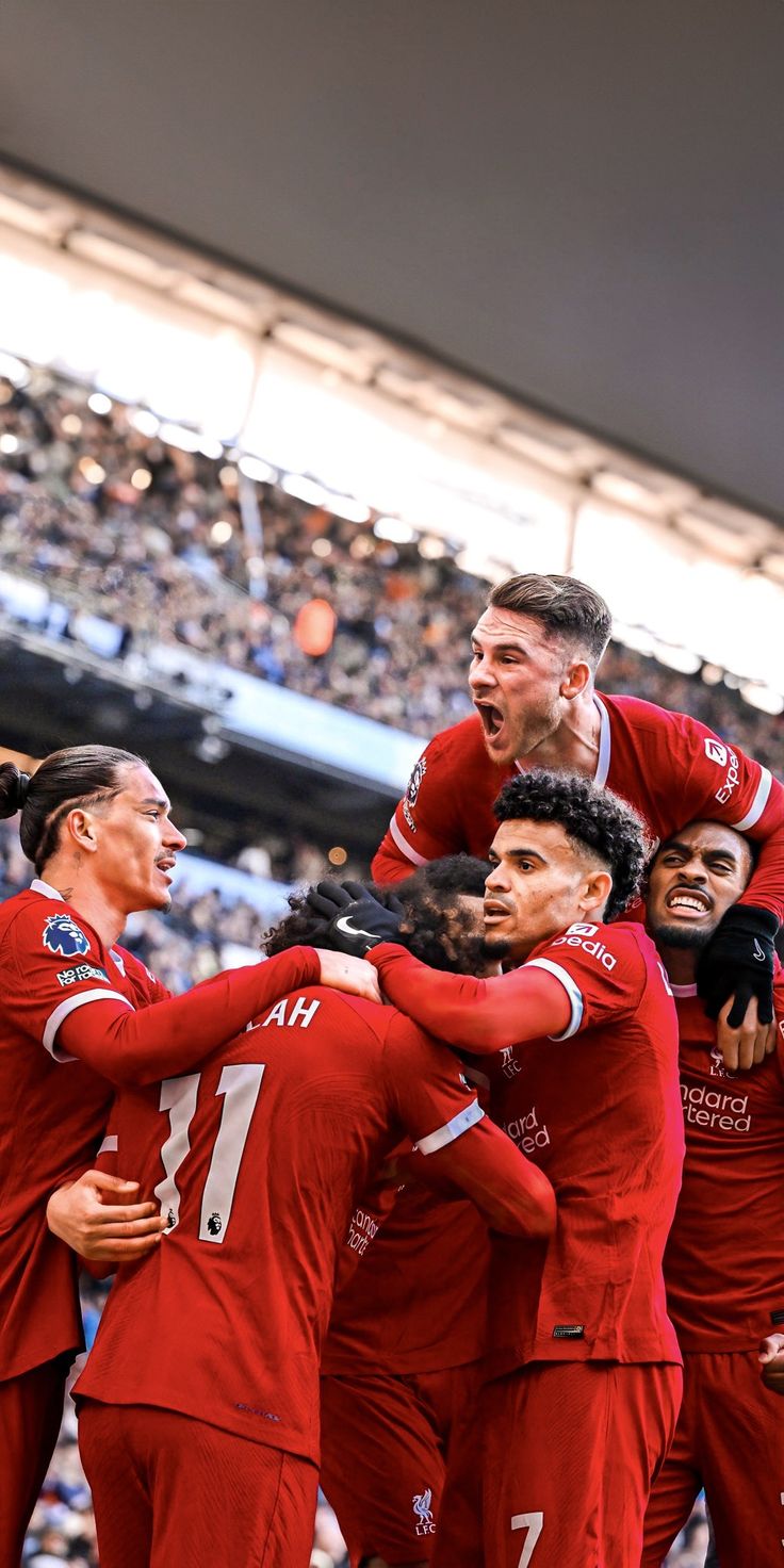 a group of men in red uniforms standing on top of each other at a soccer game