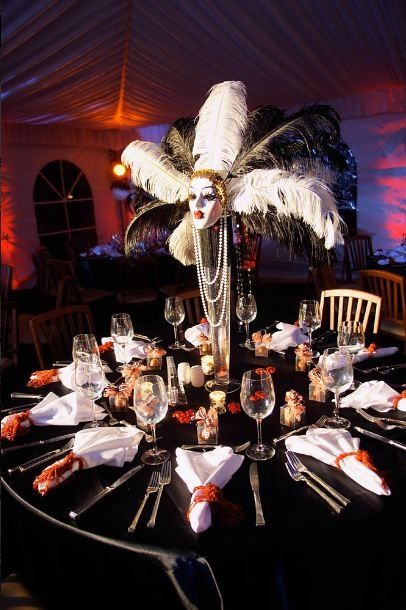 a table topped with plates and glasses covered in white feathered headdresses