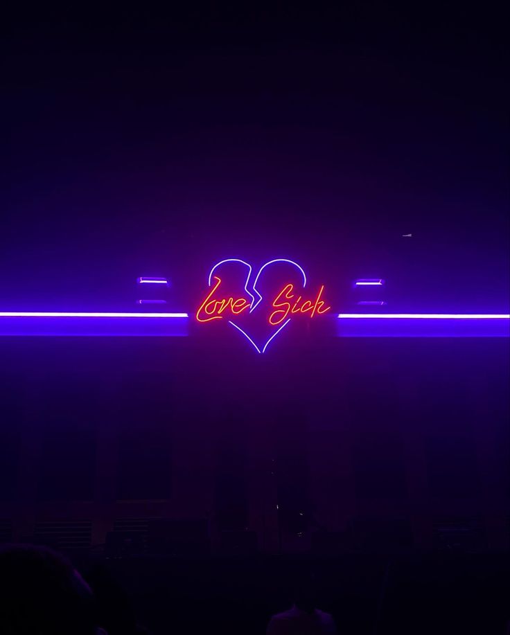 a neon sign that says love block in the middle of a dark room filled with people