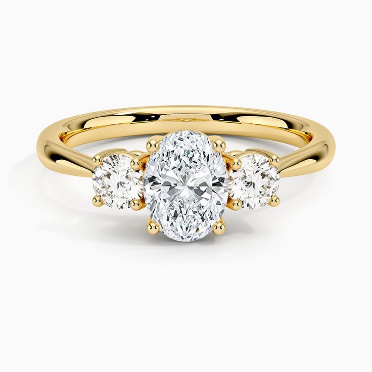 a three stone engagement ring with an oval cut diamond in the center