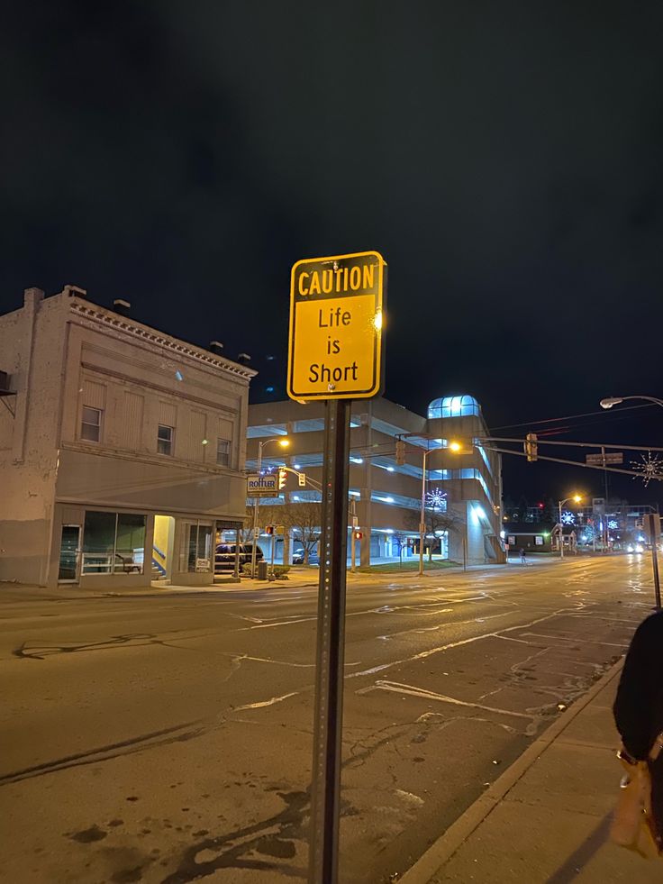 a yellow street sign sitting on the side of a road next to a tall building