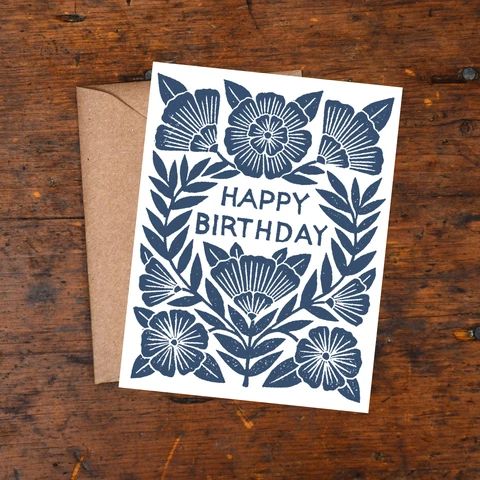 a card with the words happy birthday written in blue on top of a wooden table