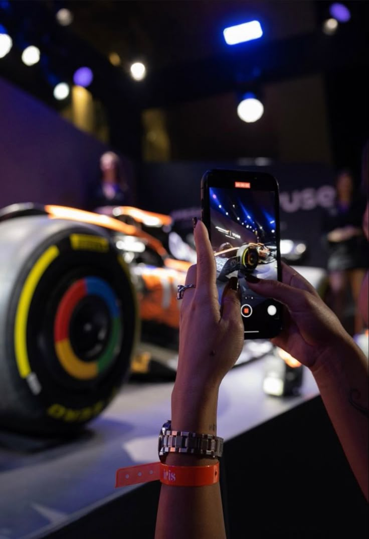 a person taking a photo of a car on their cell phone at an auto show