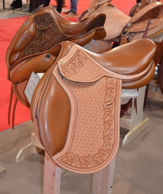 several saddles are lined up on wooden stands