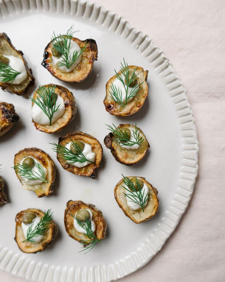 small appetizers are arranged on a white plate with green garnishes