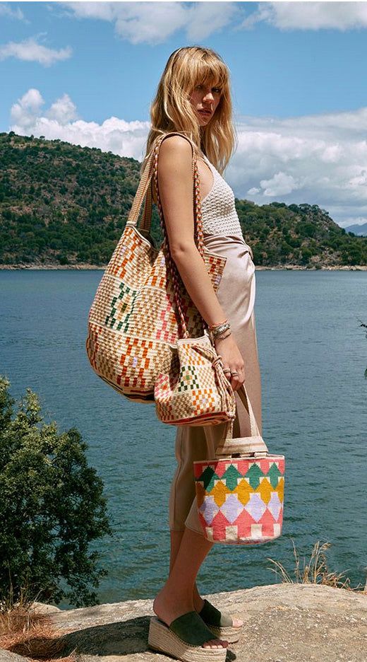 Guanabana's classic tote bag has transformed the classic shopping bag with eye-catching geometric designs and vibrant hues, giving it a unique chic and bohemian vibe. Designed in Madrid and expertly hand-woven by Wayuu artisans in Colombia, this bag features a loose knit and a long, comfortable strap, making it a go-to accessory. The result is a versatile unisex bag that you'll find indispensable. The artisans weave the bases using their designs, so each base is unique and works as their tradema Bohemian Beige Bags For Shopping, Bohemian Beige Shopping Bags, Bohemian Brown Bucket Bag With Double Handle, Bohemian Bags With Removable Pouch For Vacation, Bohemian Woven Shoulder Bag For Shopping, Multicolor Double Handle Bucket Bag For Travel, Bohemian Crochet Satchel Bag For Shopping, Bohemian Top Handle Bags For Vacation, Large Capacity Multicolor Bucket Bag With Double Handle