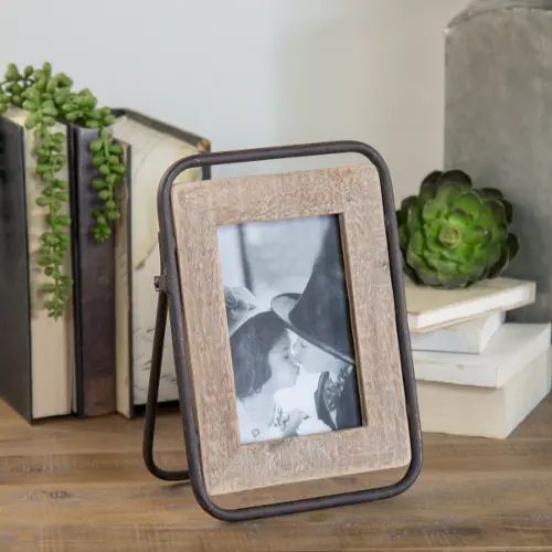 an old photo frame sitting on top of a wooden table next to books and cacti