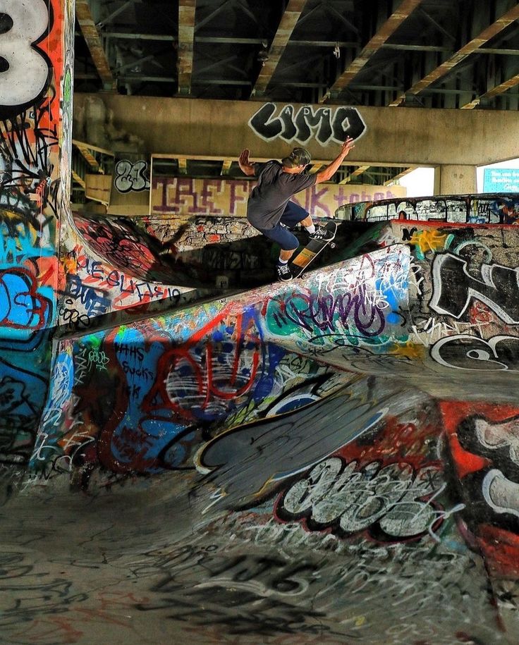 a man riding a skateboard up the side of a ramp covered in grafitti