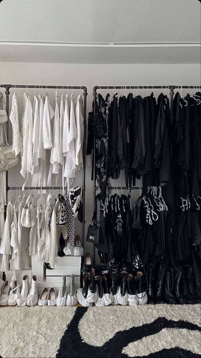 a closet filled with lots of white and black clothing hanging on the wall next to shoes