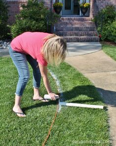 a woman is watering her lawn with a hose