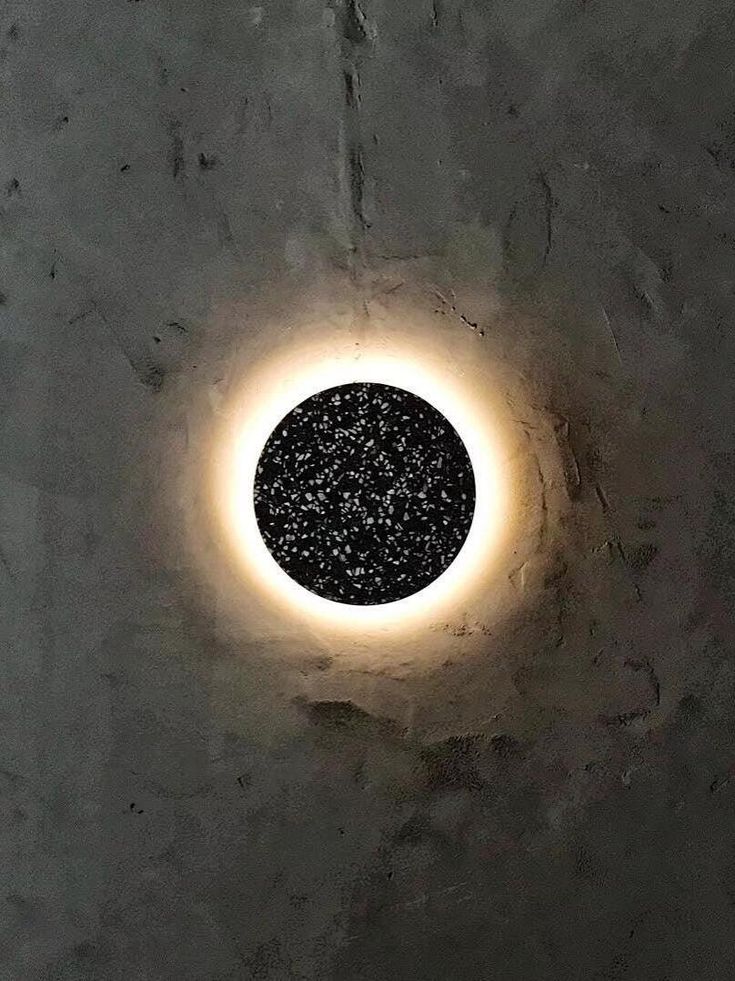 a circular light that is on the side of a wall with black dots in it