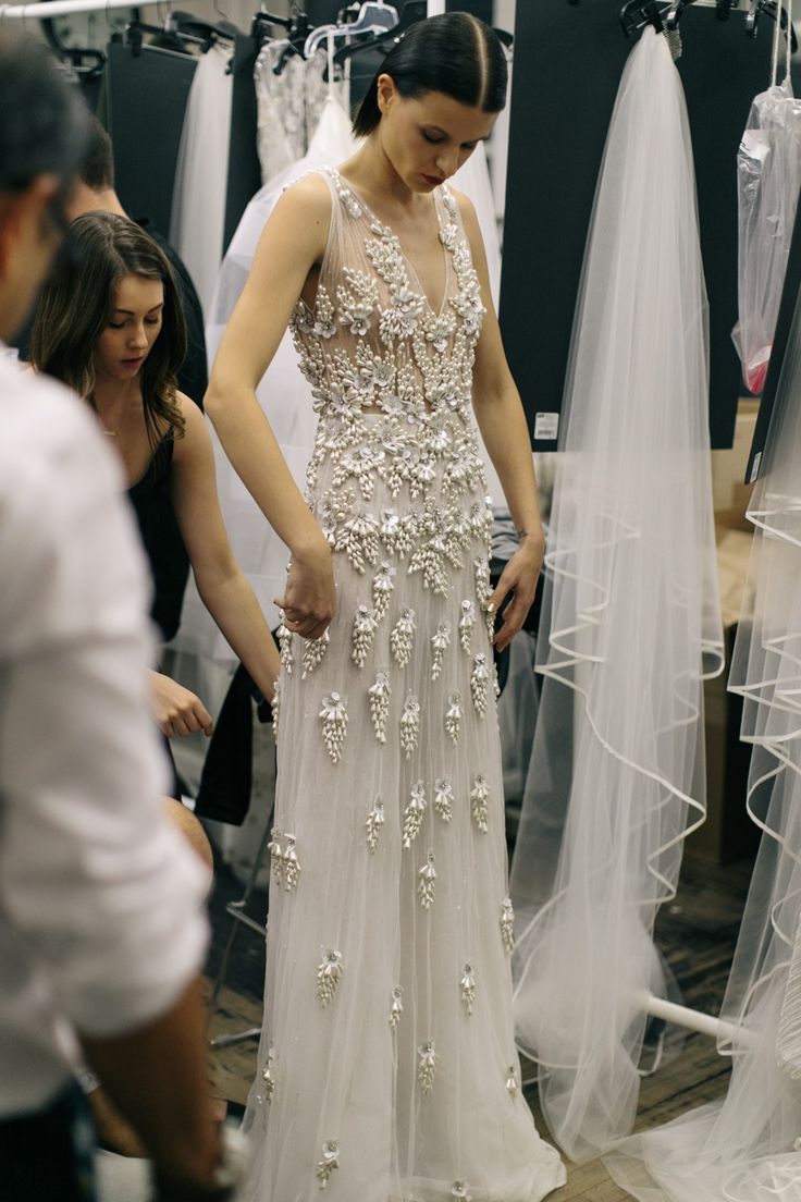 a woman standing in front of a wedding dress