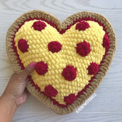 a crocheted heart with red and yellow flowers is held up by a person's hand