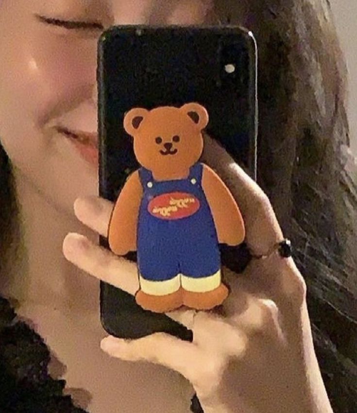 a woman holding up a cell phone with a bear on the front and back of it