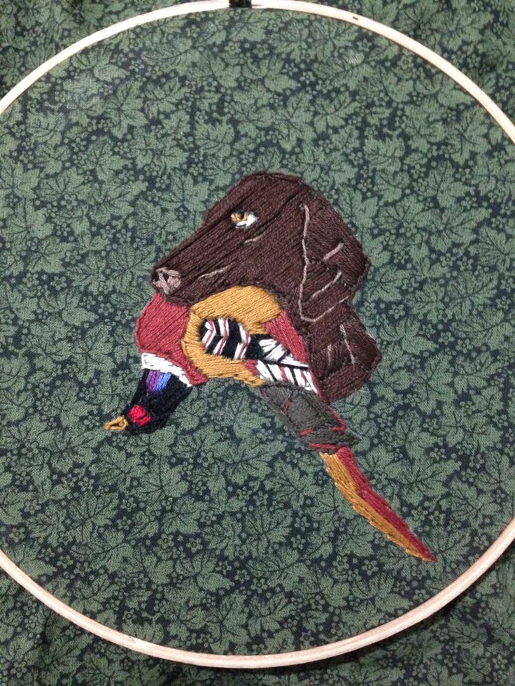 an embroidered bird sitting on top of a wooden hoop